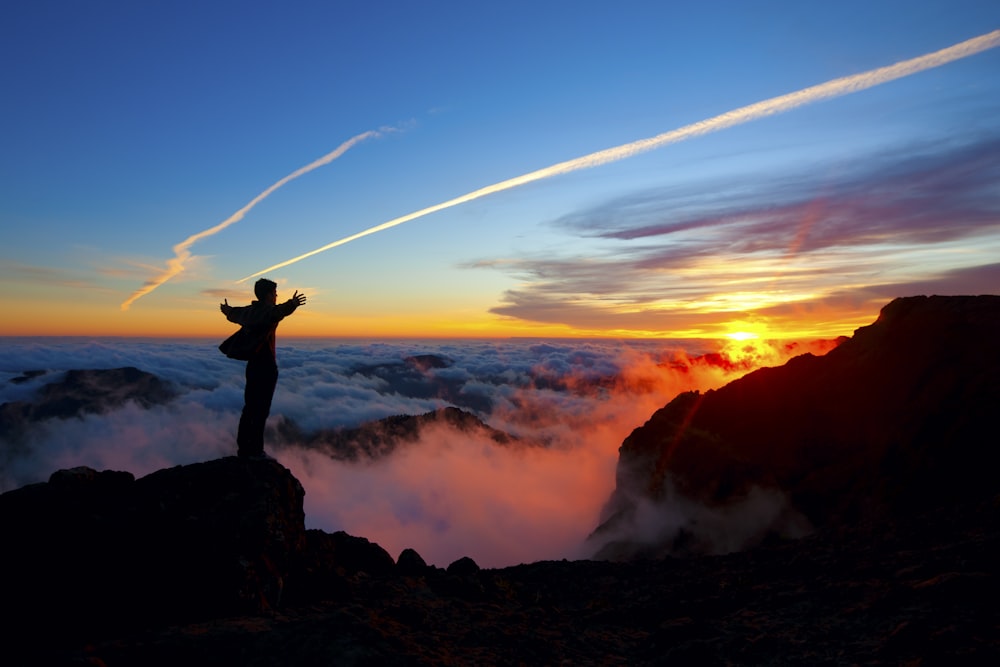 a man standing on top of a mountain at sunset