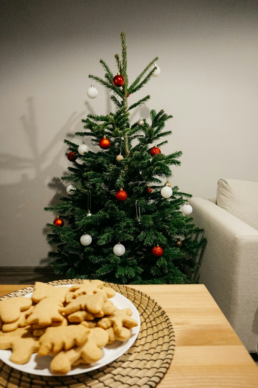a plate of cookies next to a christmas tree