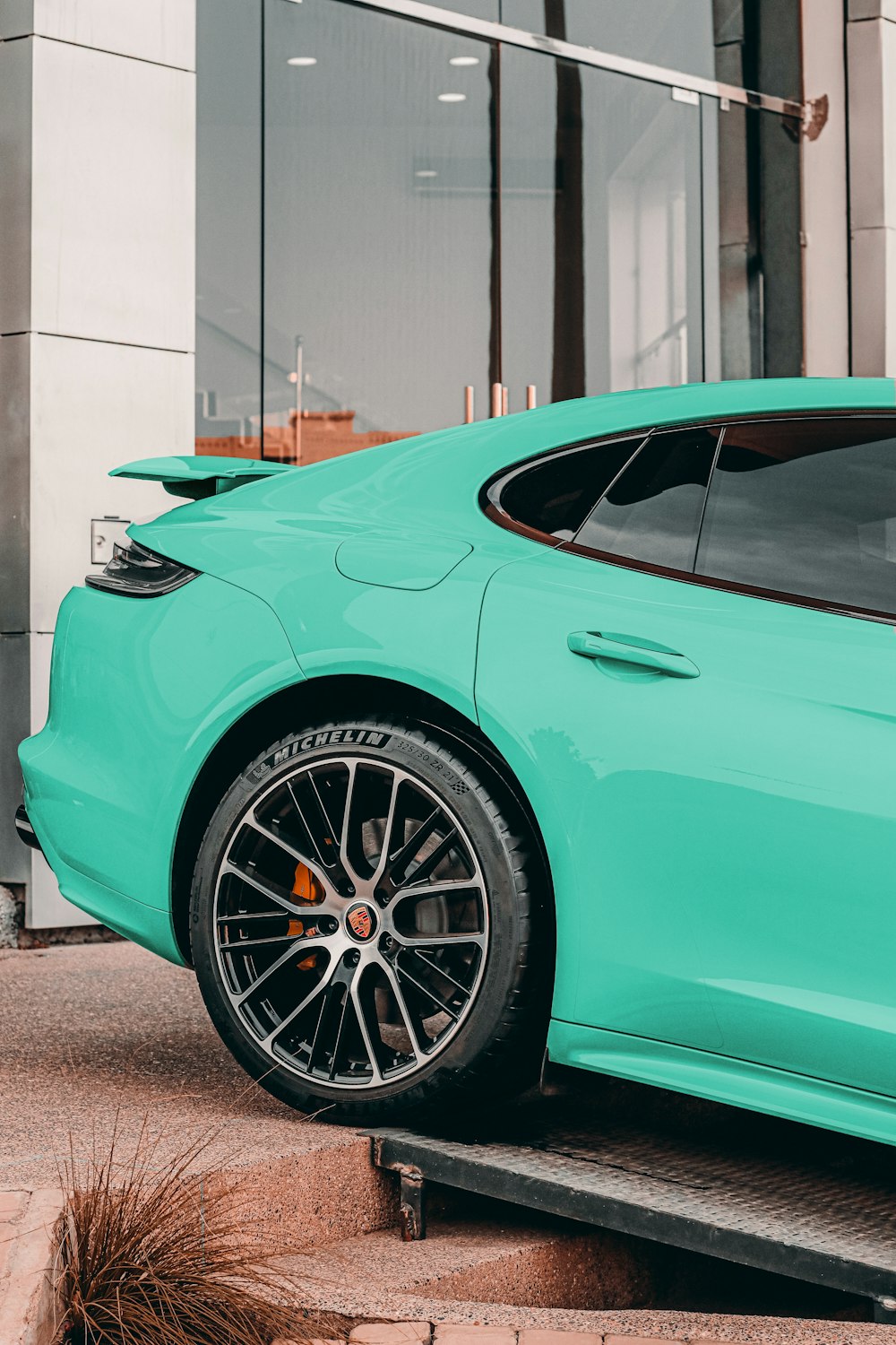a turquoise sports car parked in front of a building