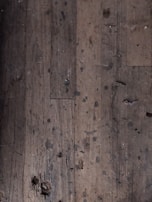 Close-up of a worn-out wooden floor before restoration, showing scratches and dullness.