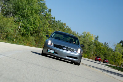 A smiling family stepping into a sleek Infinity taxi on a sunny day.