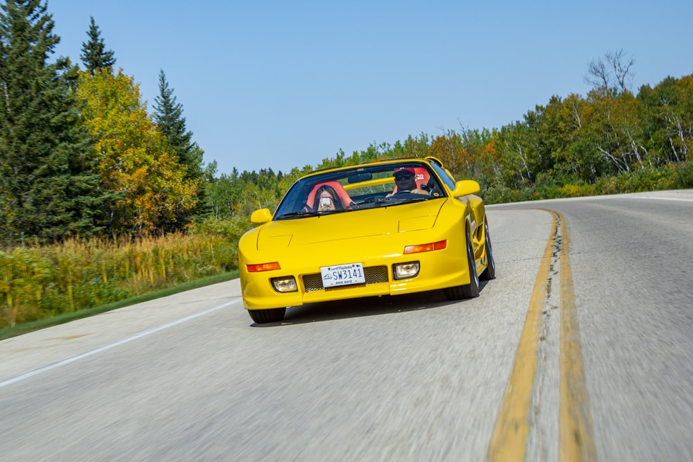 a yellow sports car driving down the road