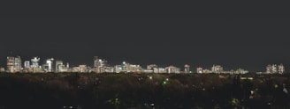 A city skyline at night with illuminated buildings.