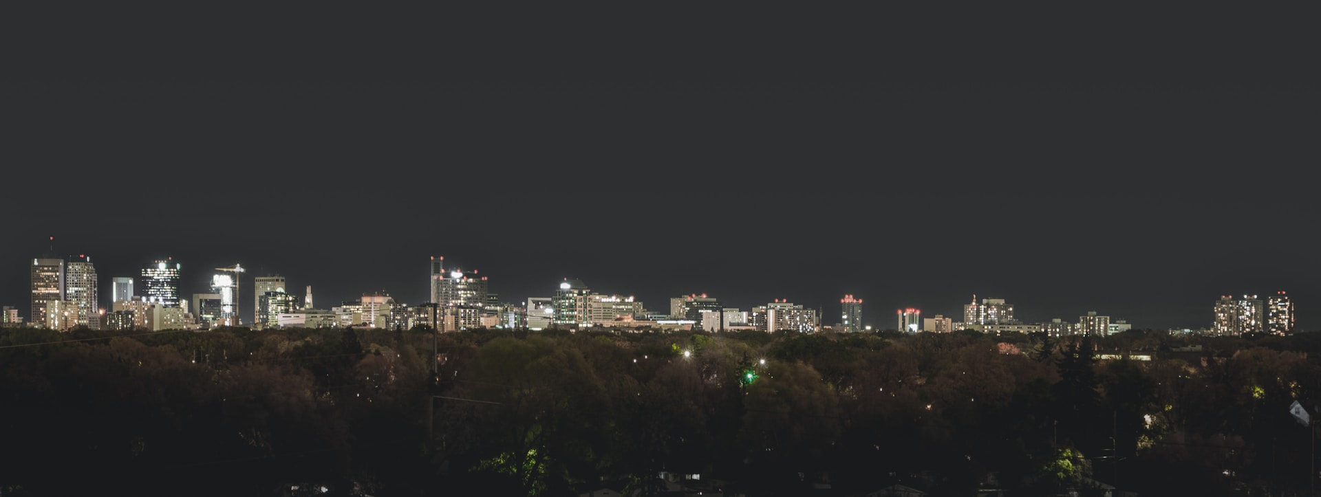 An urban skyline at night, illuminated by city lights against a starry sky.