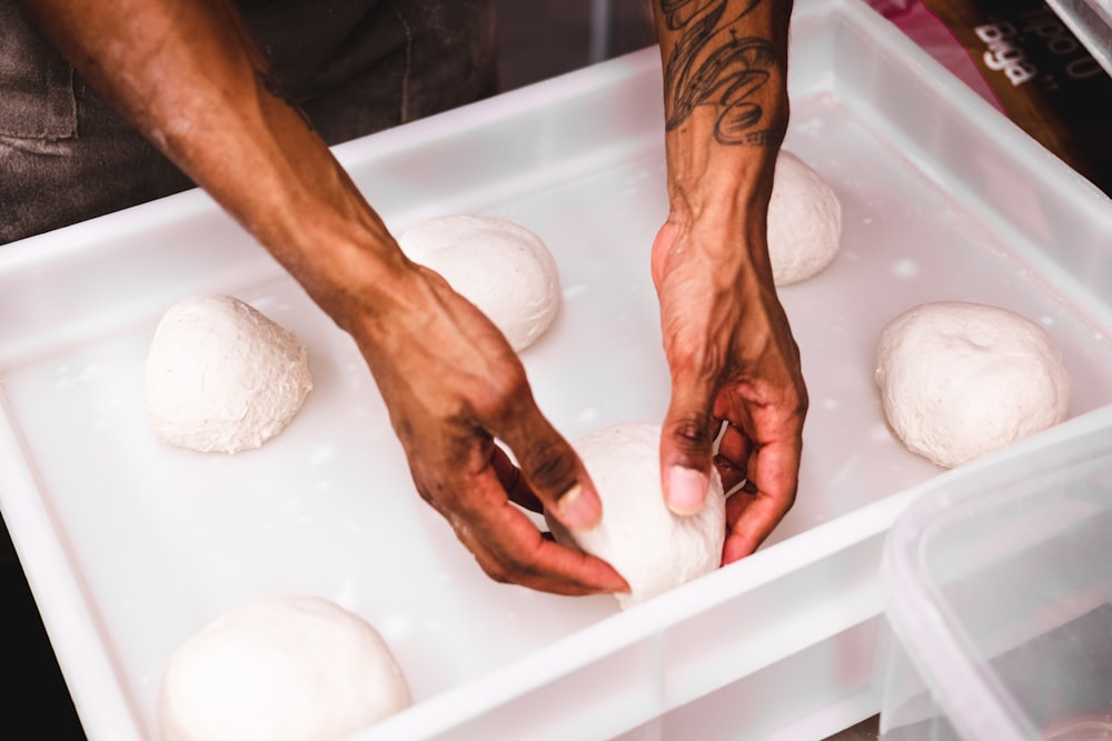 a close up of a person putting dough into a container
