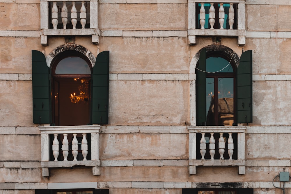 a building with two balconies and green shutters