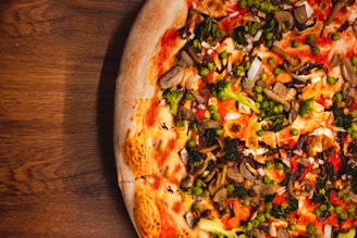 Fresh vegetables and colorful toppings arranged on a green-themed pizza.