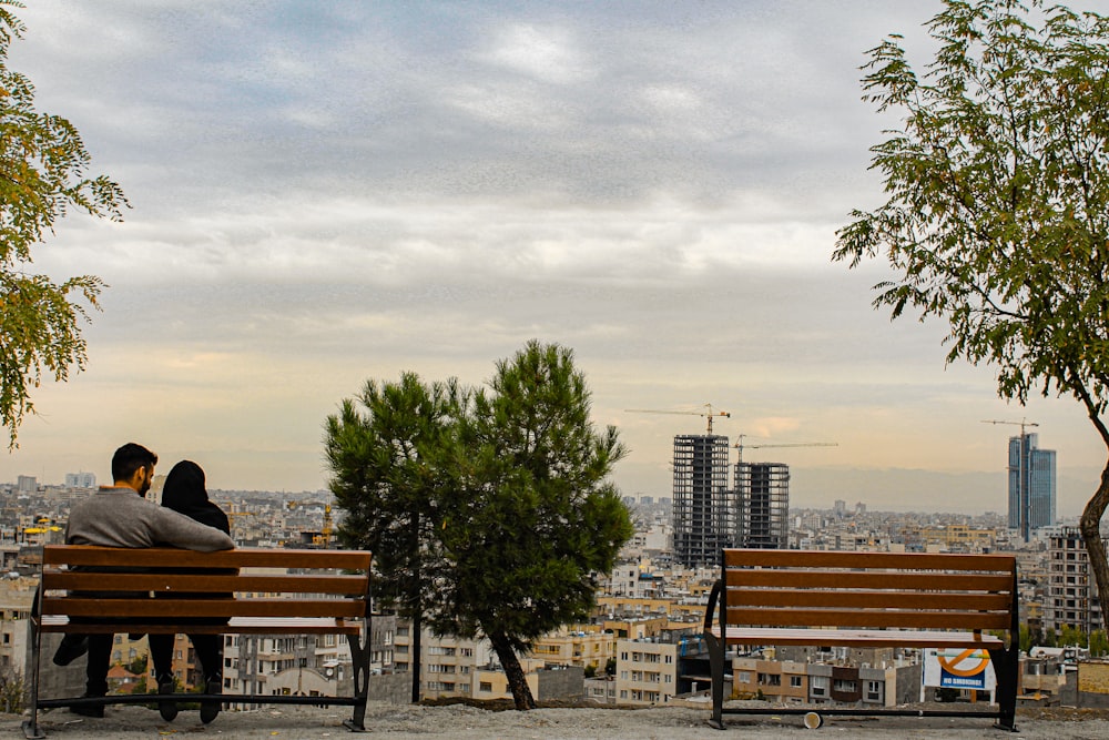 two people sitting on a bench overlooking a city