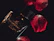 A shadowy silhouette of a perfume bottle against a backdrop of deep red rose petals.