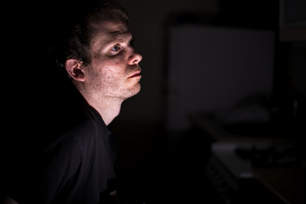 a man in a dark room looking up at something