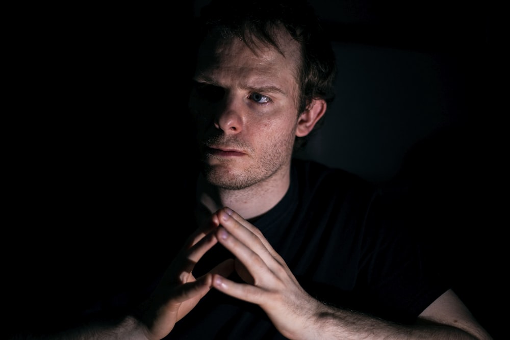 a man in a dark room holding his hands together