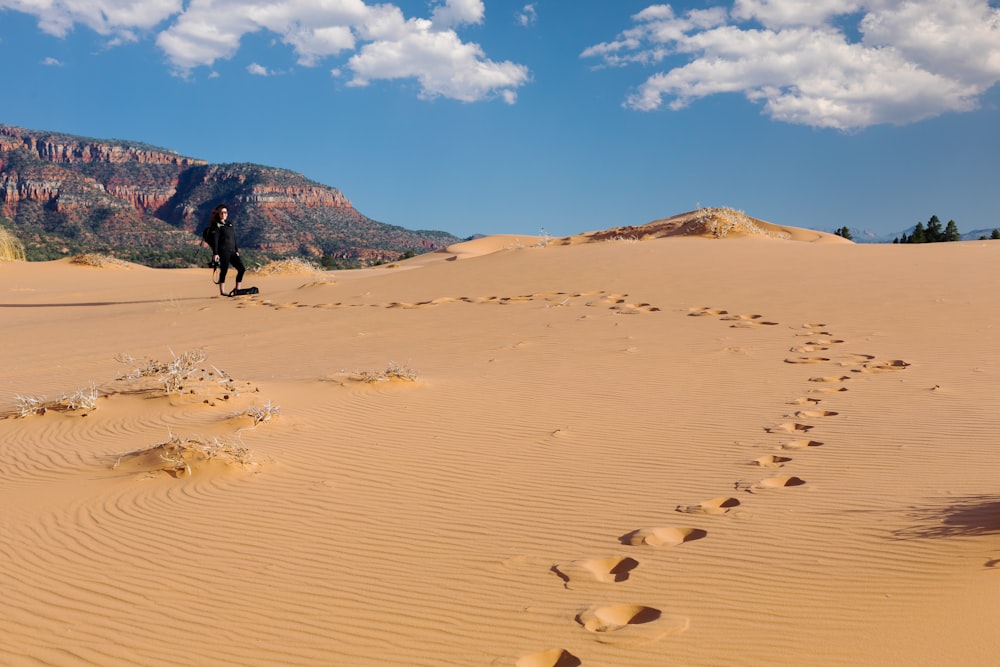 a person walking across a desert with a mountain in the background