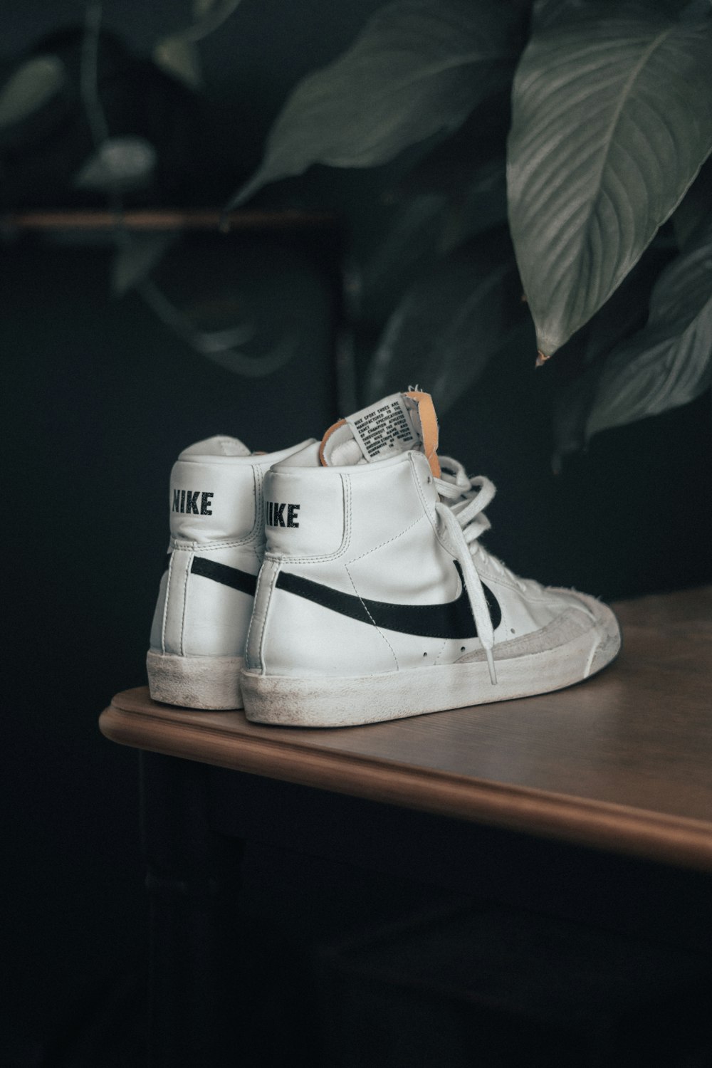 a pair of white sneakers sitting on top of a wooden table