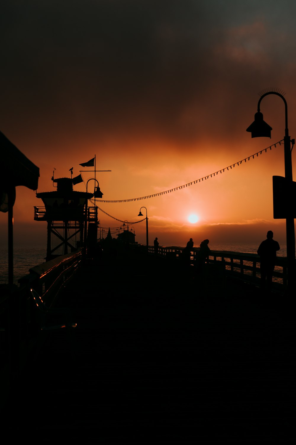 the sun is setting over a pier with people on it