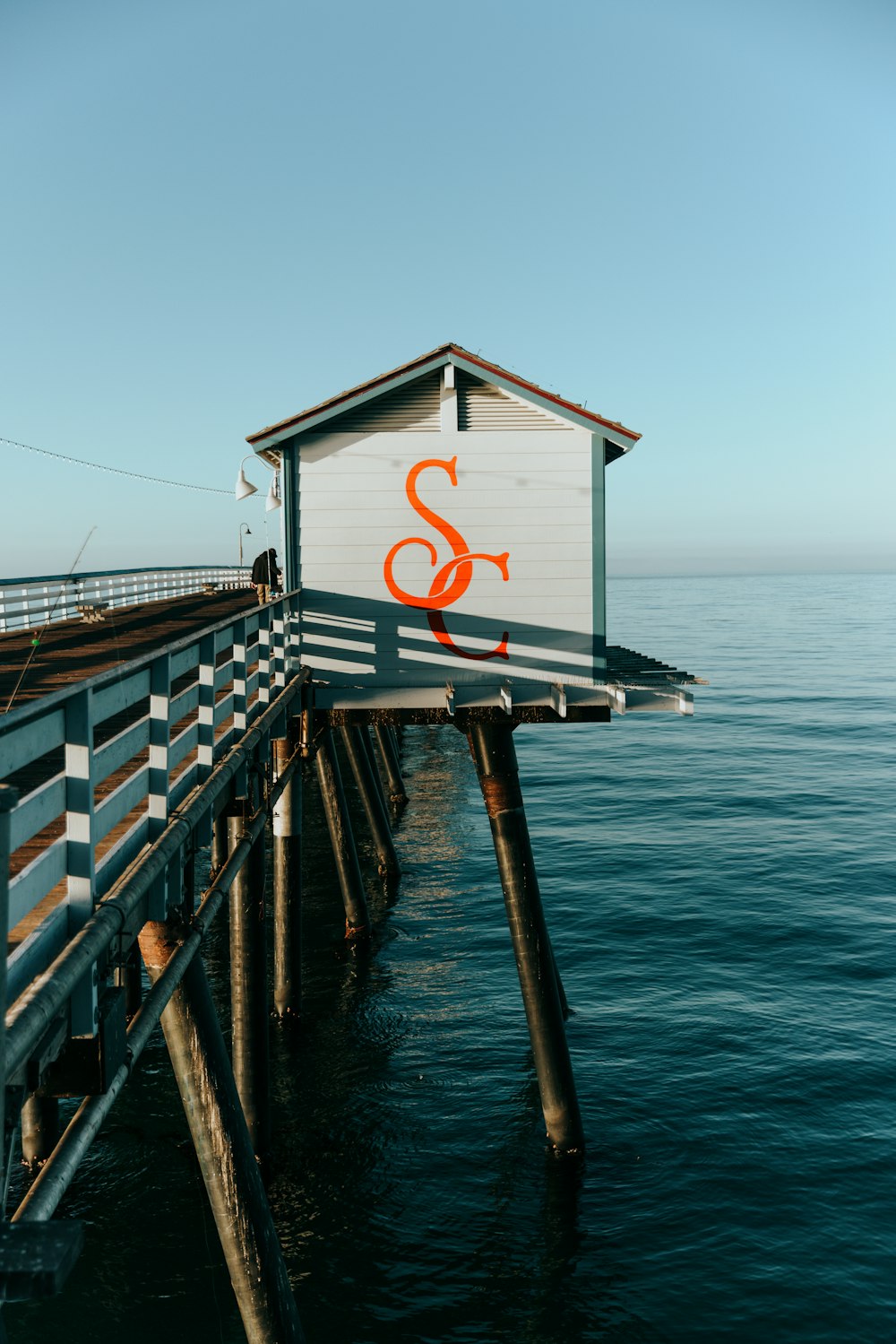 a house sitting on top of a pier next to the ocean