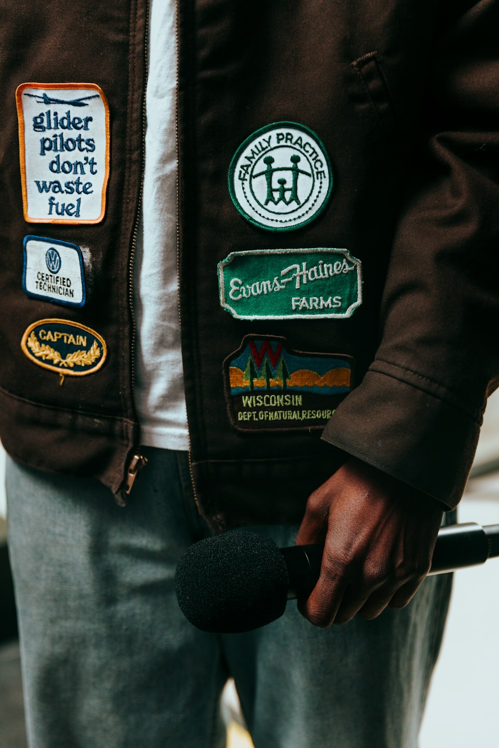 a man wearing a brown jacket and holding a microphone