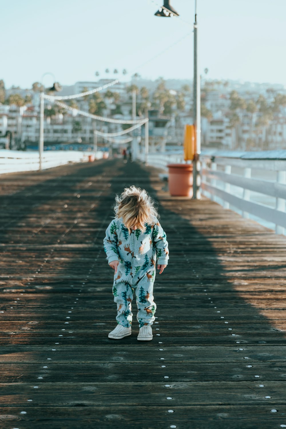 a little girl standing on a wooden pier