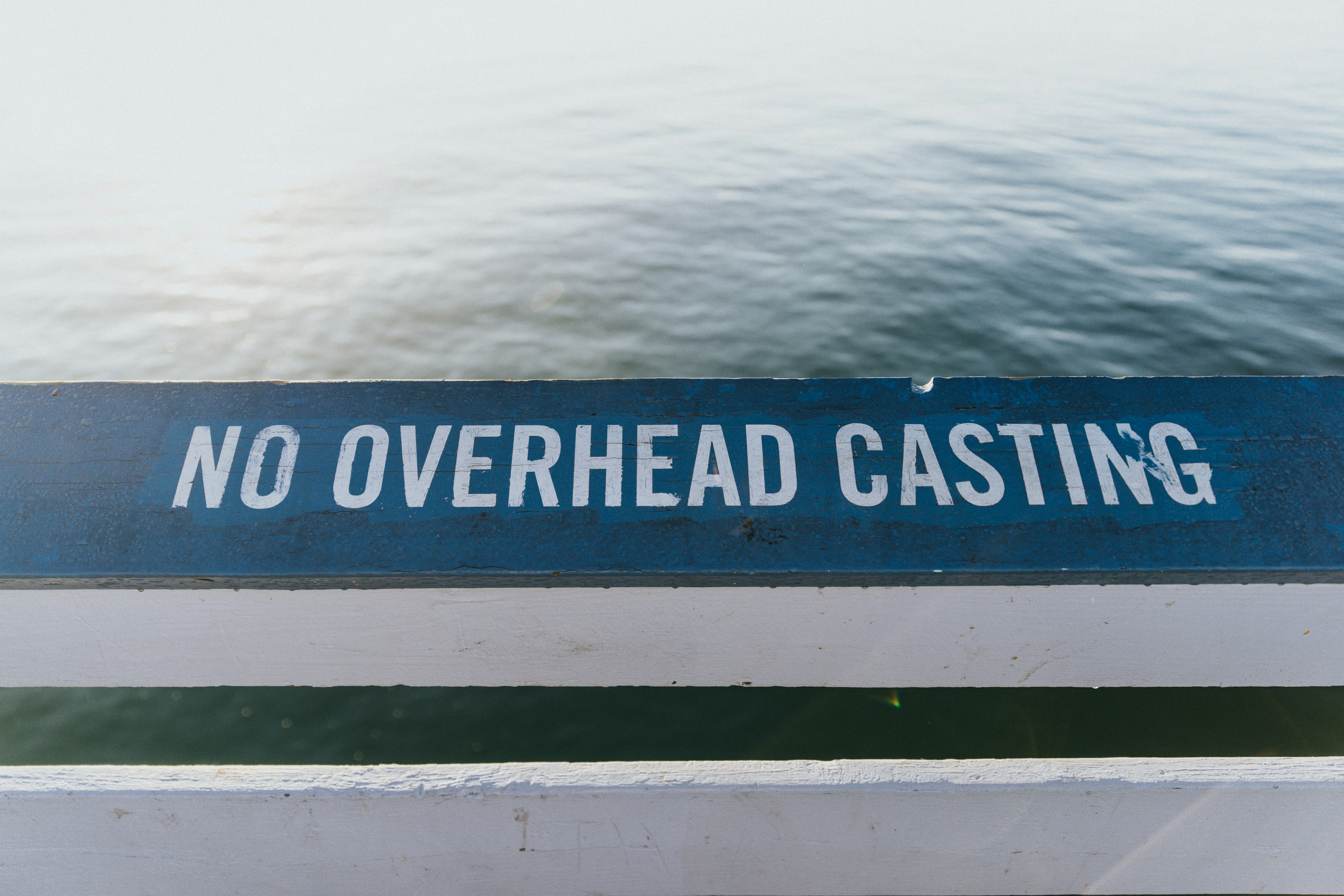 A sign that says no overhead casting on a railing
