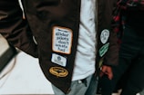a close up of a person wearing a jacket with stickers on it
