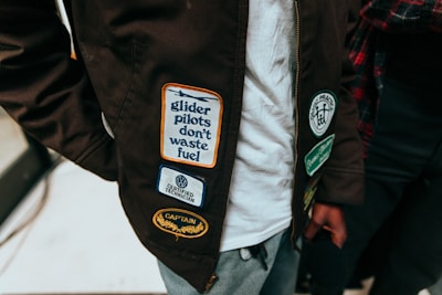 a close up of a person wearing a jacket with stickers on it