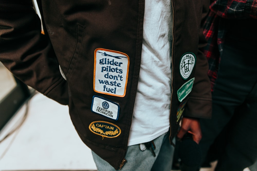 a close up of a person wearing a jacket with stickers on it