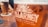 A close-up view of a glass filled with beer from Killarney Brewing Company, featuring a golden amber color. The frothy head is visible at the top of the glass, with the company's logo and slogan printed prominently in white on the glass surface. In the background, another similar glass of beer is slightly blurred, resting on a table.