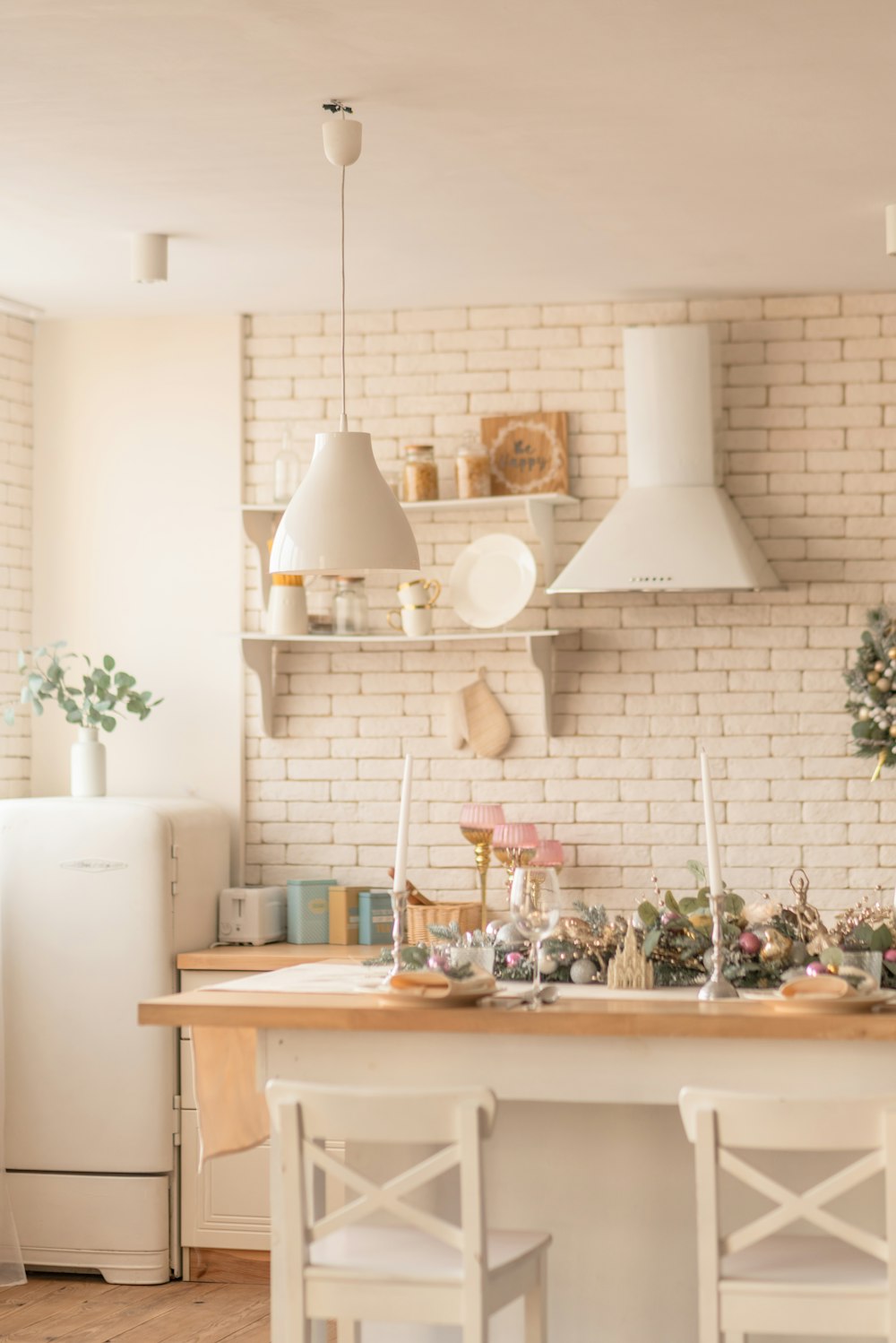 a kitchen with a white brick wall and a wooden table