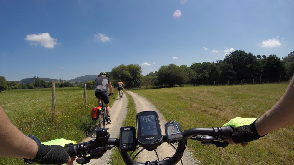 a couple of people riding bikes down a dirt road