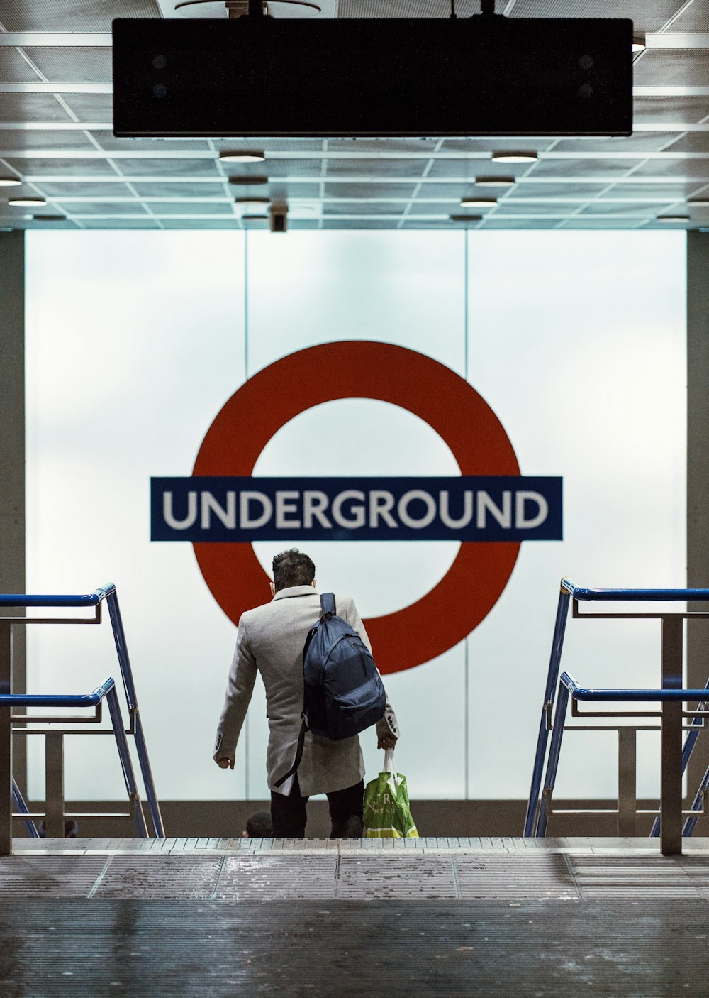 a man with a backpack is standing in front of a underground sign