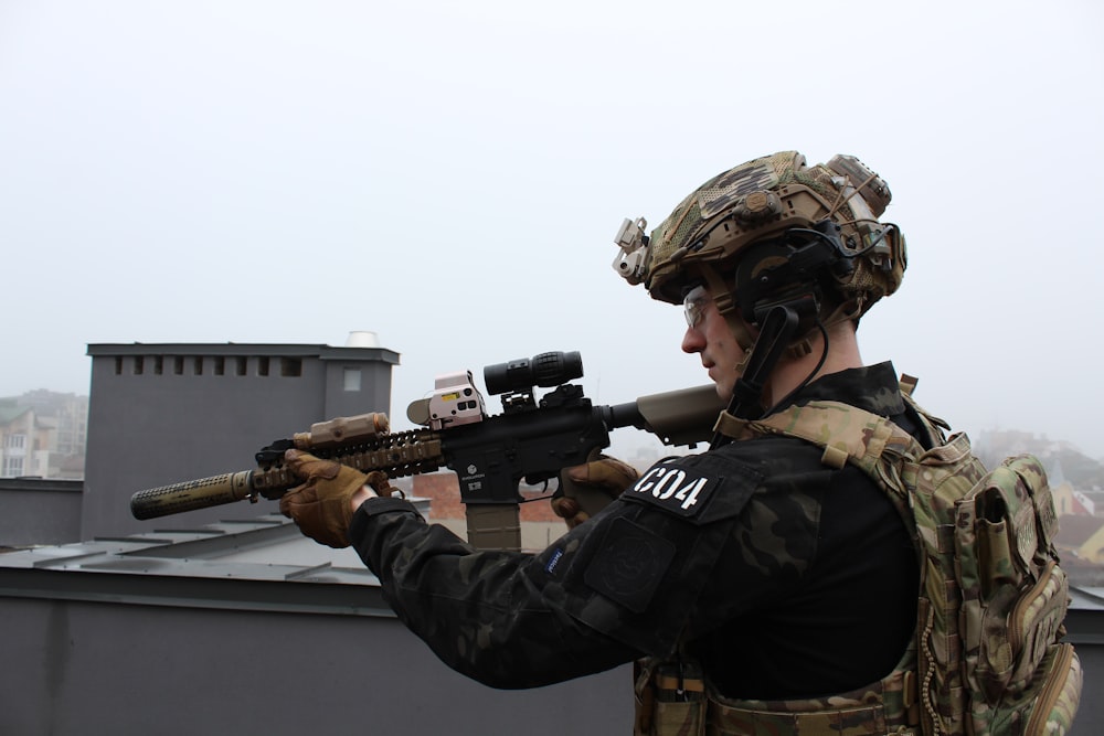 a man holding a rifle on top of a roof