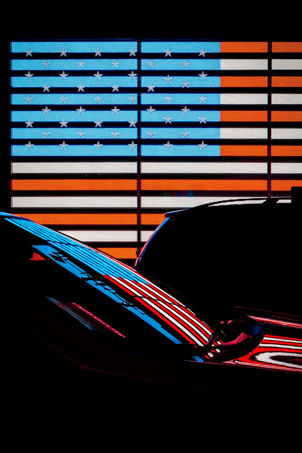 a car parked in front of a large american flag