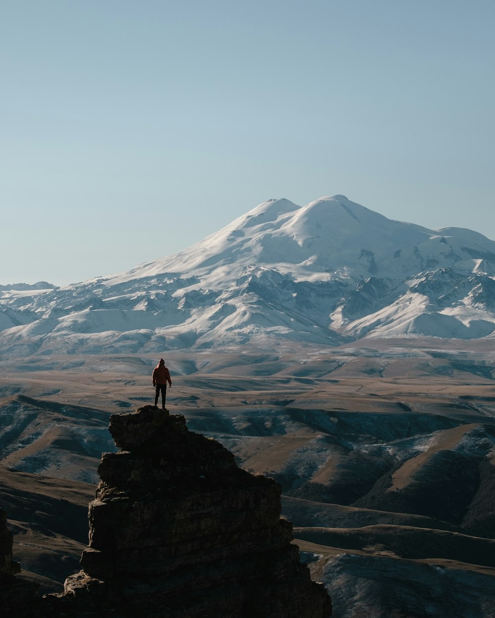 Una persona parada en la cima de una gran montaña