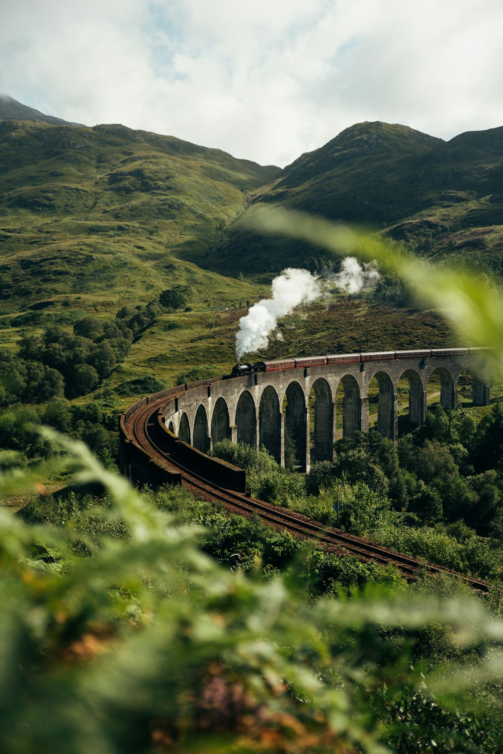 a train traveling over a bridge in the mountains