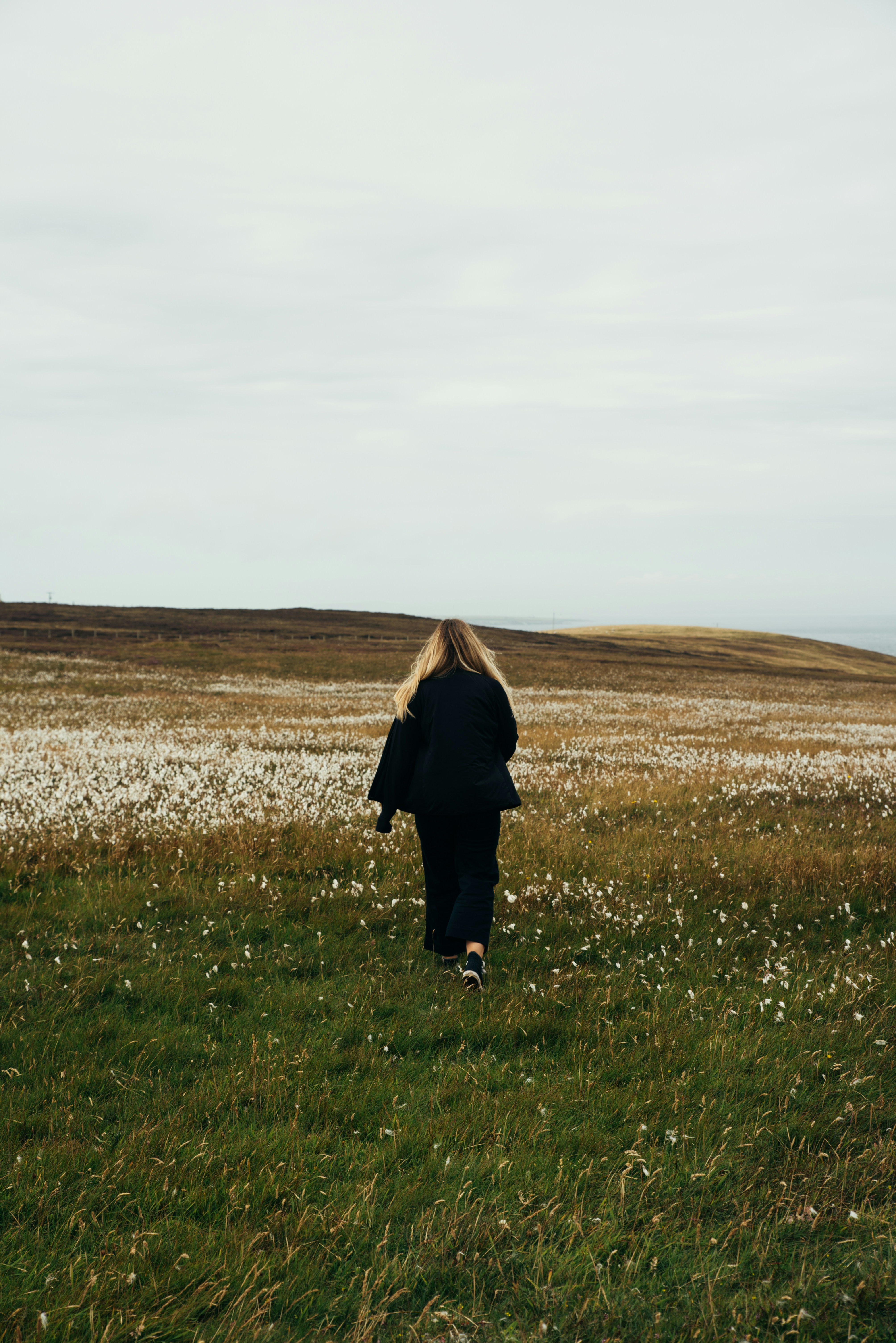 a woman walking through a field of flowers