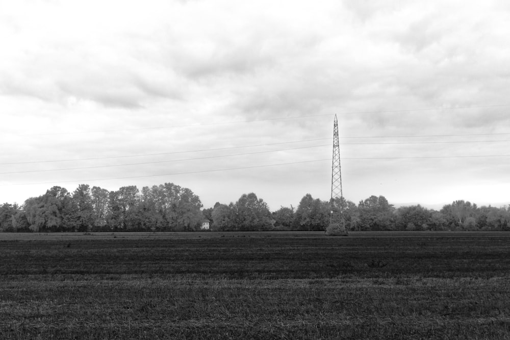 a black and white photo of a field with power lines in the background