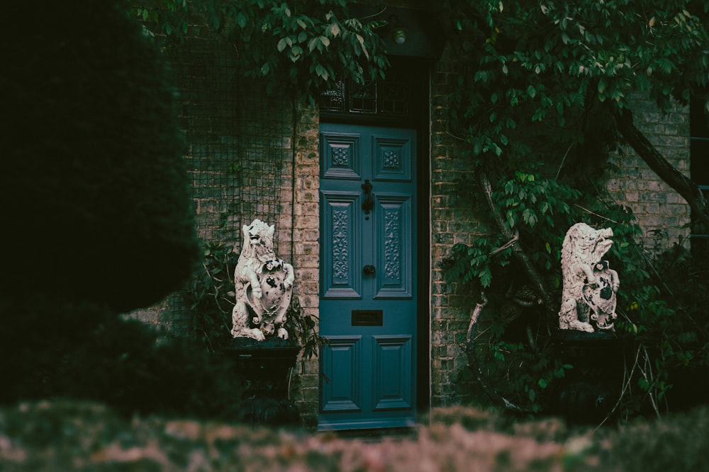 a blue door and two statues in front of a brick building