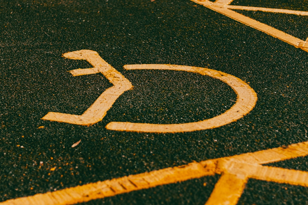 a handicapped sign painted on the asphalt of a parking lot