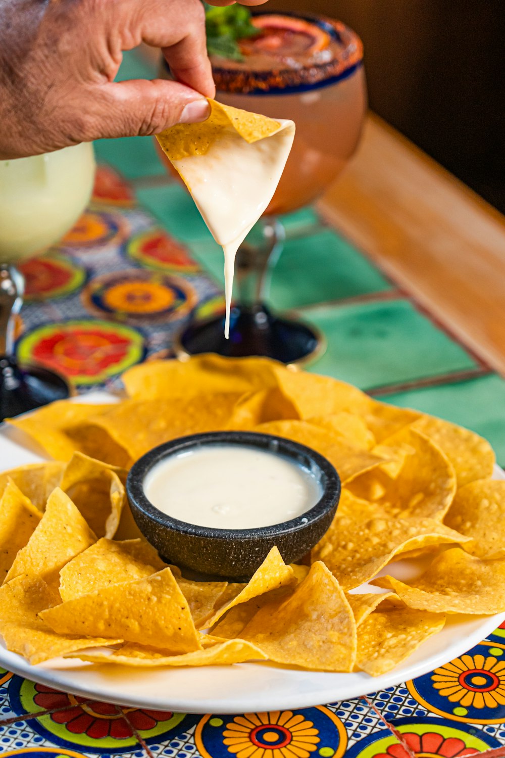 a person dipping a tortilla into a bowl of salsa