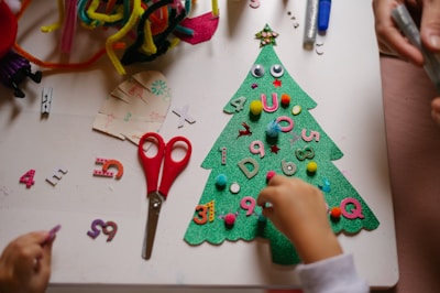 a child is making a christmas tree out of felt
