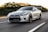A sleek sports car speeding down a winding road at sunset.
