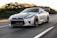 A sleek sports car speeding down a winding road at sunset.