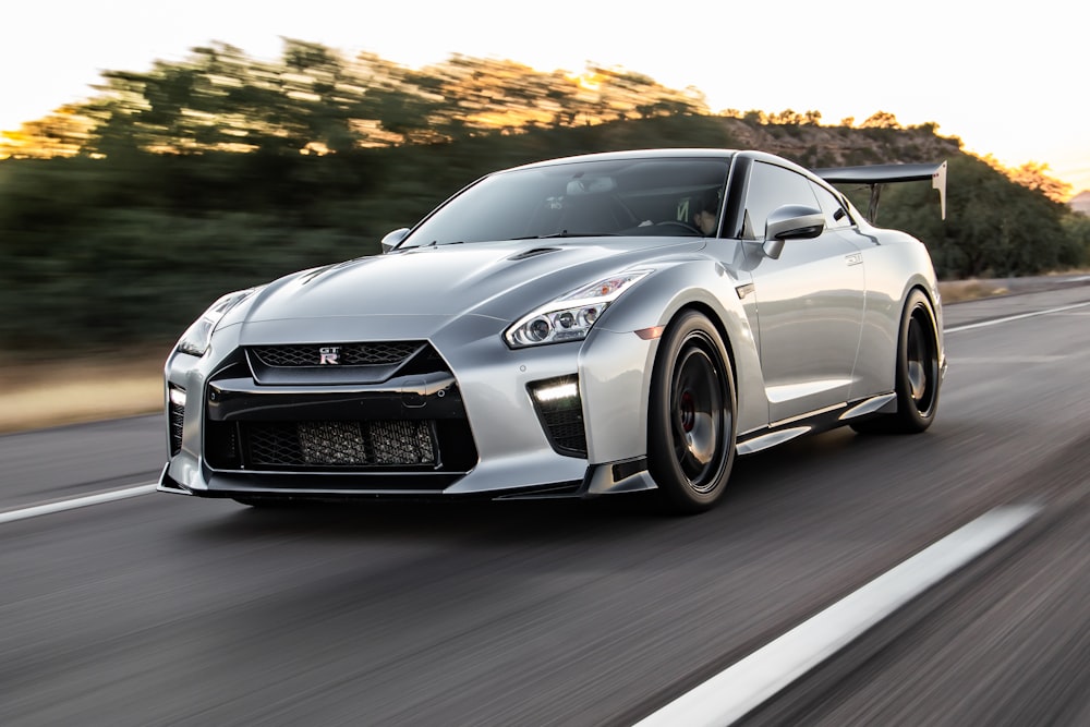 a silver sports car driving down a road