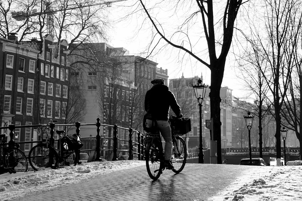 a man riding a bike down a snow covered sidewalk