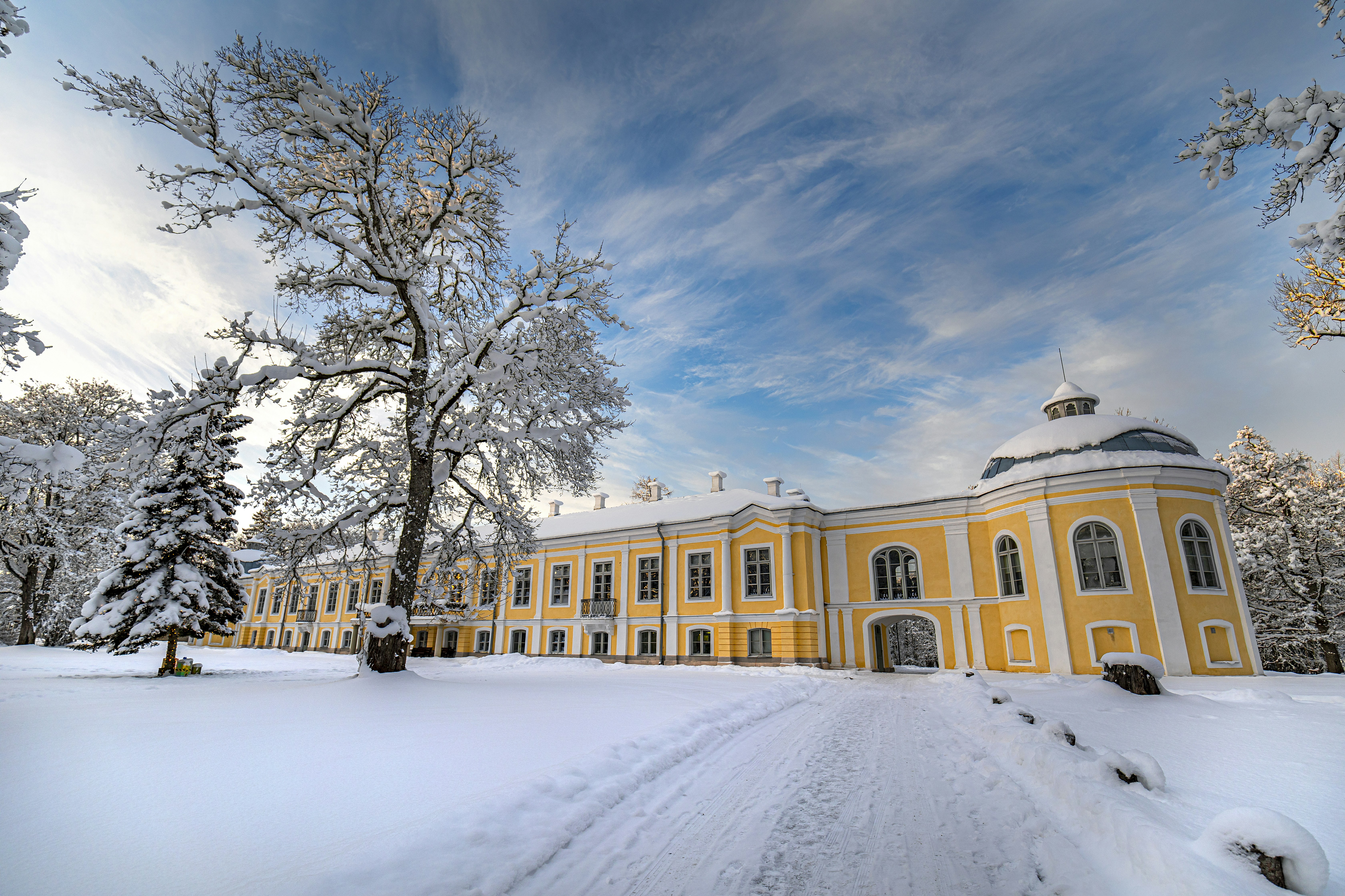 a large yellow building surrounded by snow covered trees