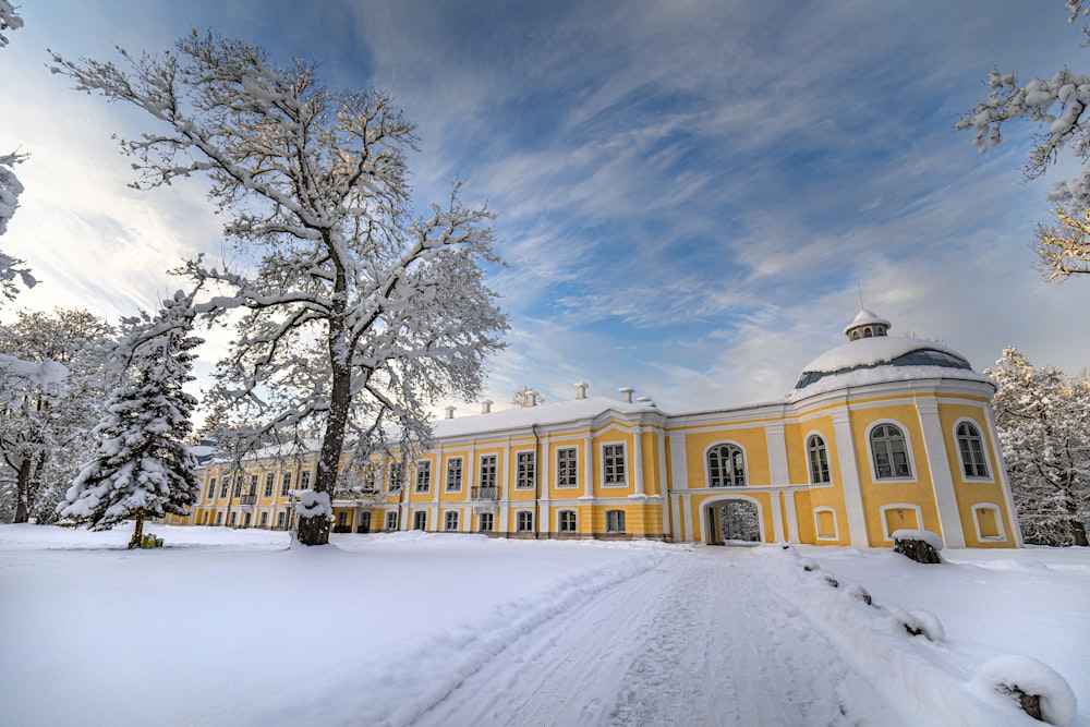 a large yellow building surrounded by snow covered trees