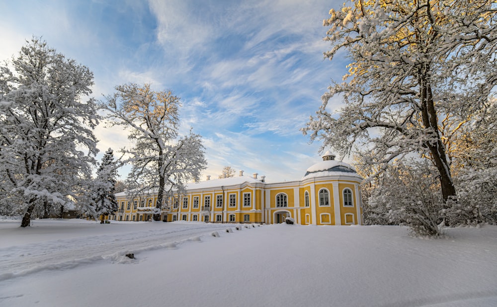 a large yellow building surrounded by snow covered trees