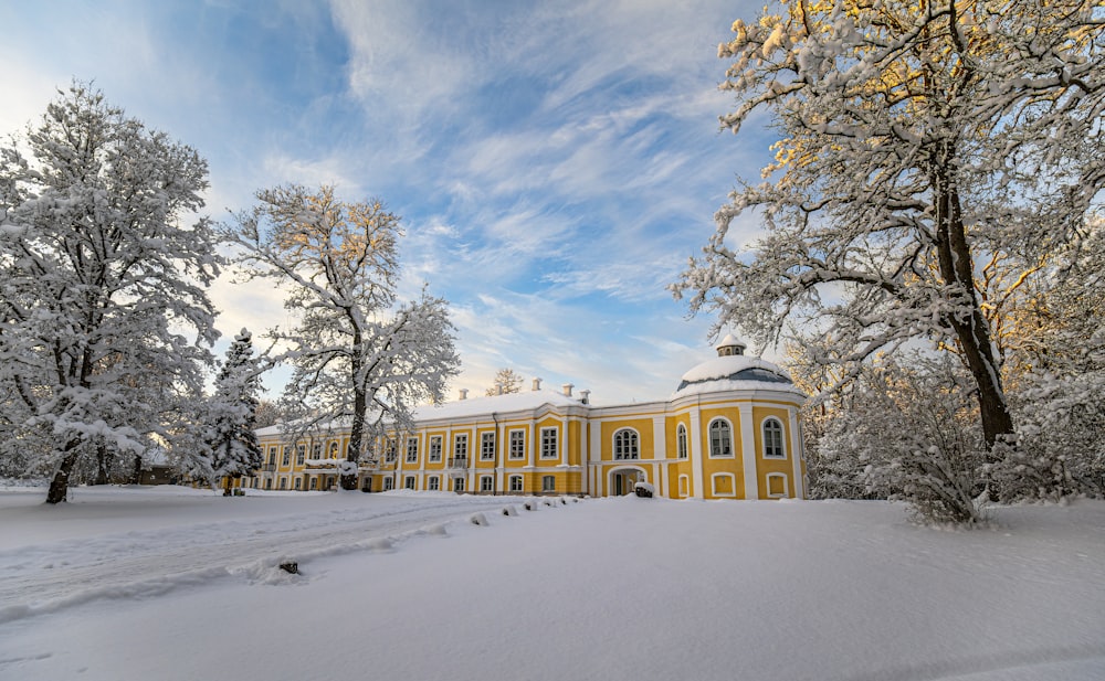 ein großes gelbes Gebäude, umgeben von schneebedeckten Bäumen