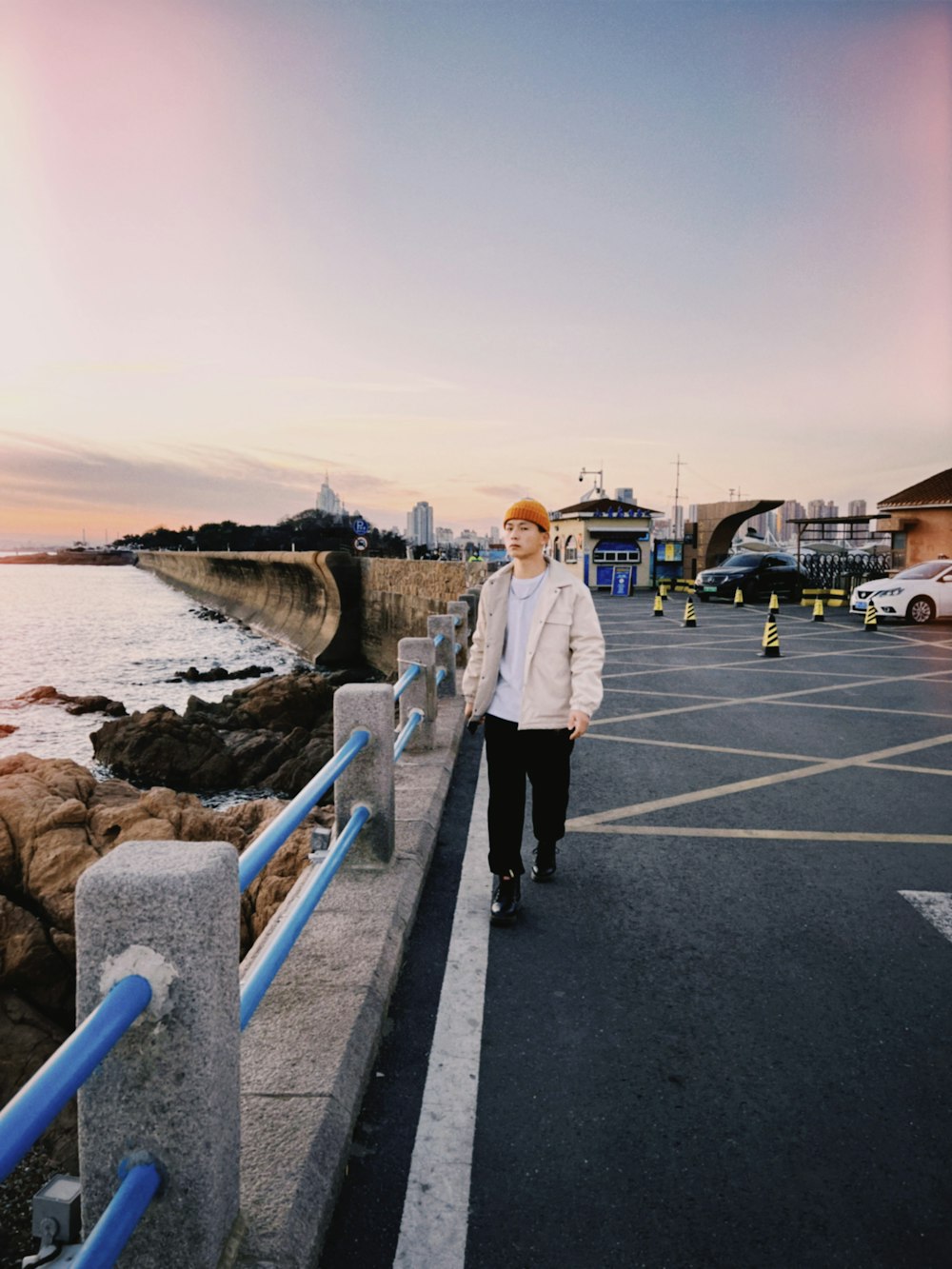 a man walking down a street next to the ocean