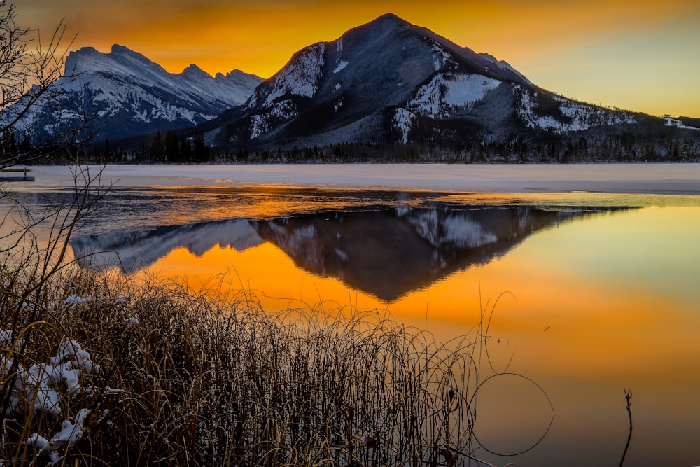 a mountain range is reflected in the still water of a lake