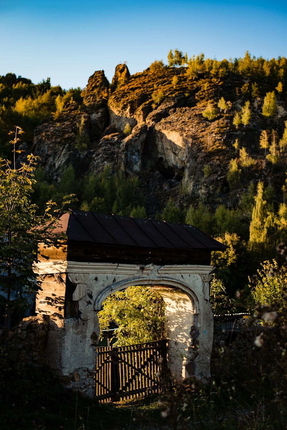 an old building with a gate in front of a mountain